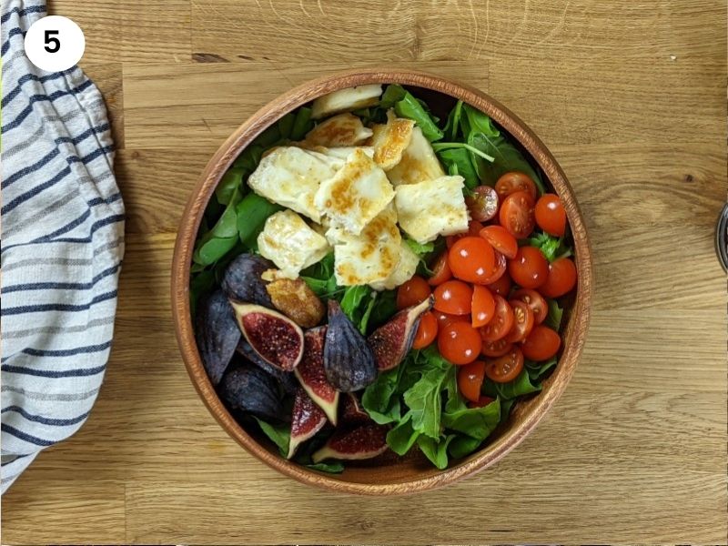Fig and grilled halloumi salad in wooden bowl before adding dressing Fig and grilled halloumi salad in wooden bowl before adding dressing.