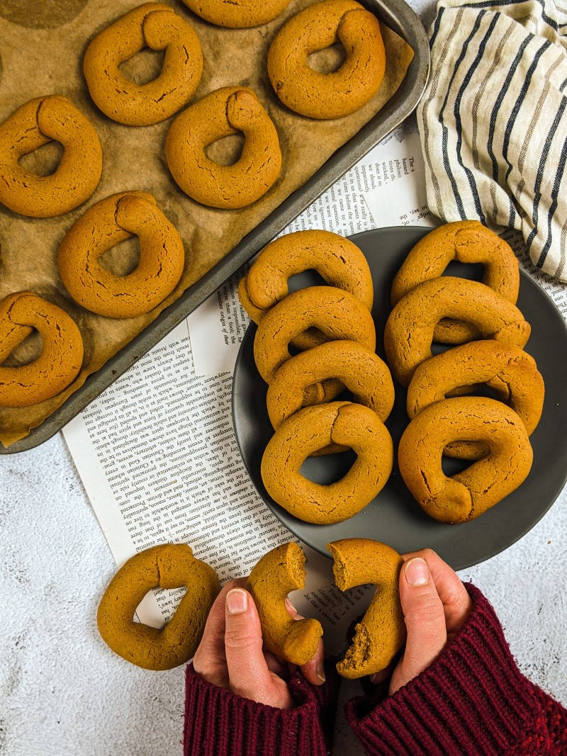 Grape molasses cookies served on a gray plate next to tray with cookies