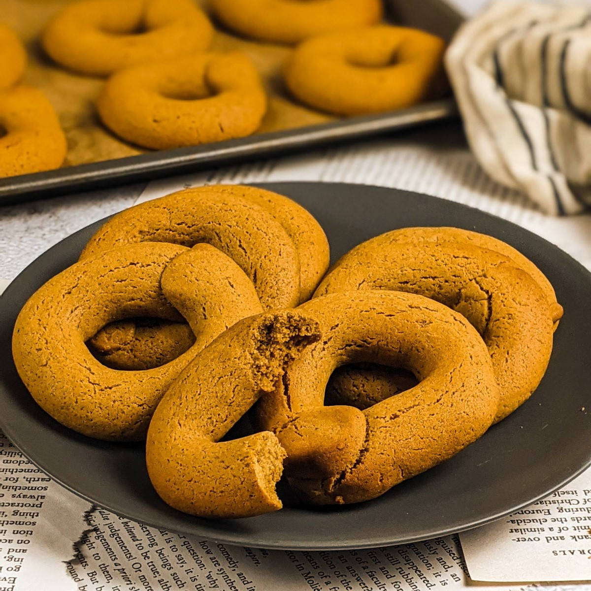 Grape molasses cookies served on a gray plate next to tray with cookies.