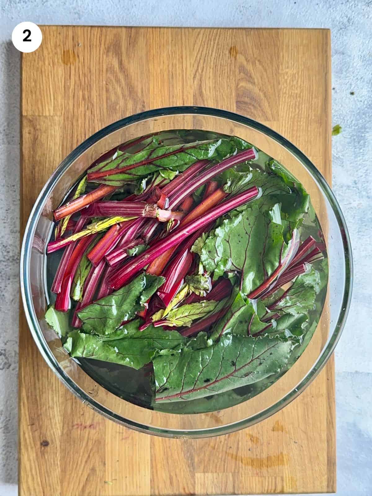 Beet leaves in a big bowl filled with water.