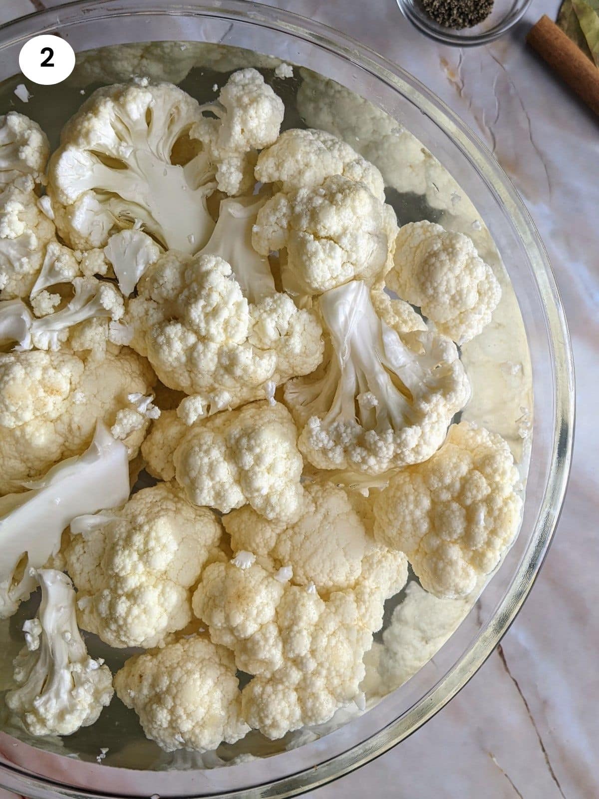 Cauliflower florets in bowl with water and vinegar.