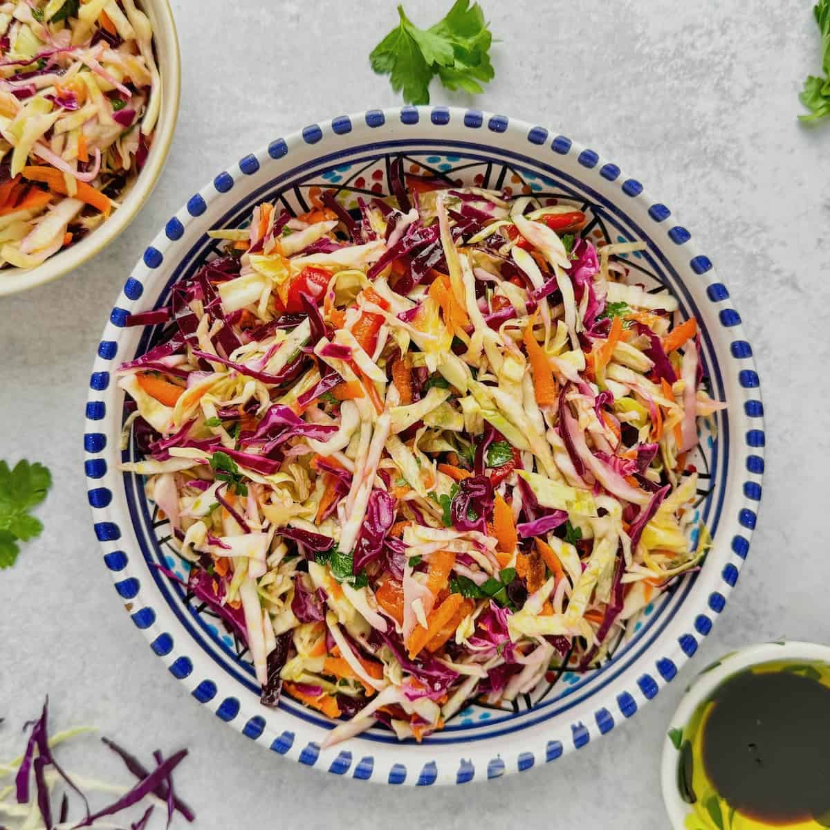 Greek cabbage salad served in bowl with cabbage slices and parsley next to the plate.