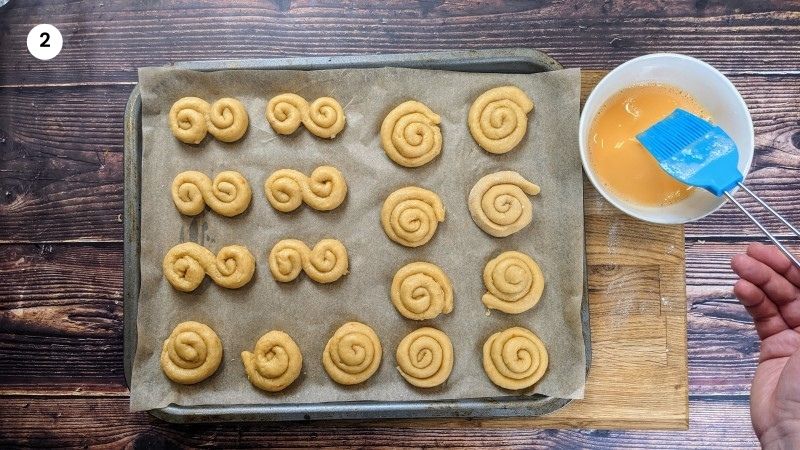 Brushing the cookies with egg wash before putting them in the oven.