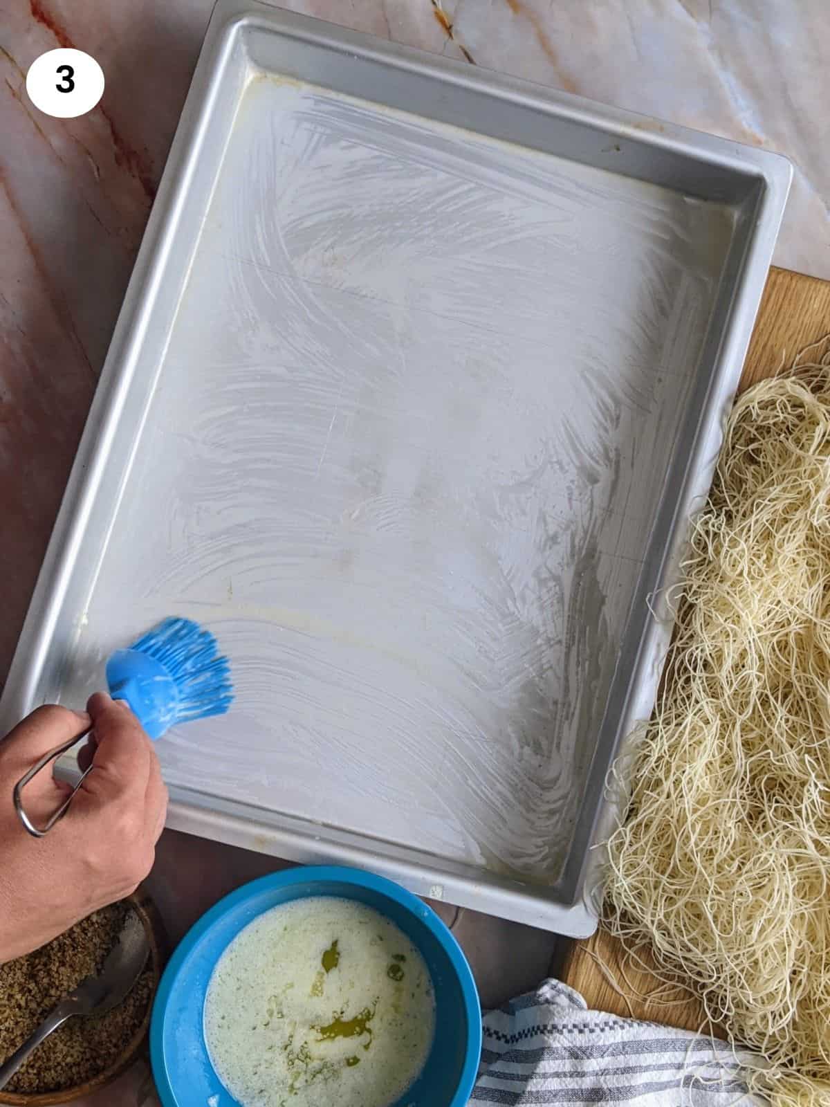 Brushing the bottom of the tray with butter.