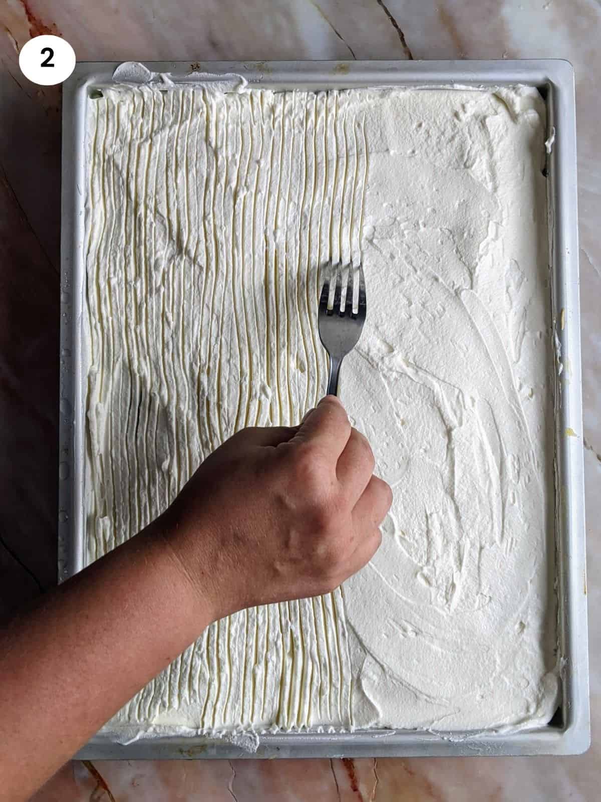 Scoring the whipped cream layer with a fork.