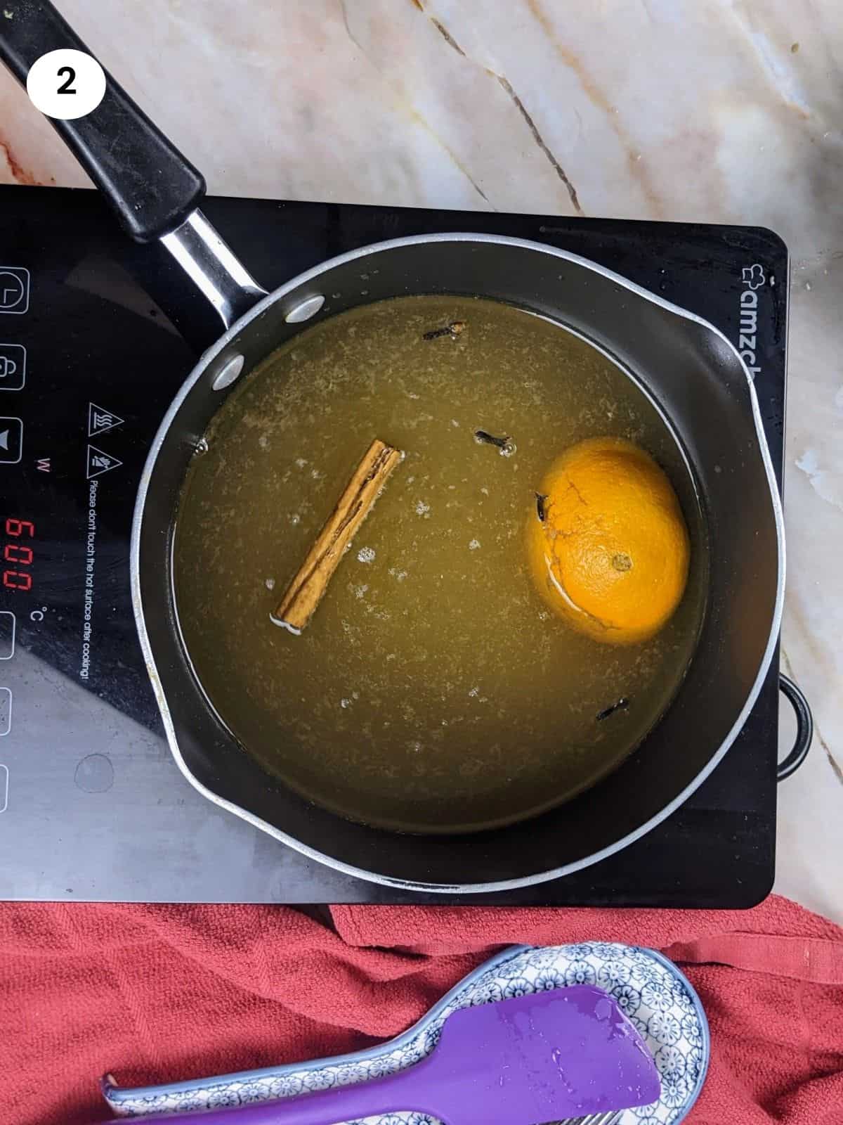 Adding the spices and orange to the pot.