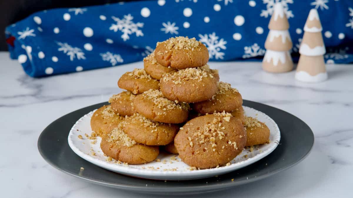 Greek honey cookies served on a plate with honey and nuts on top Greek honey cookies served on a plate with honey and nuts on top.