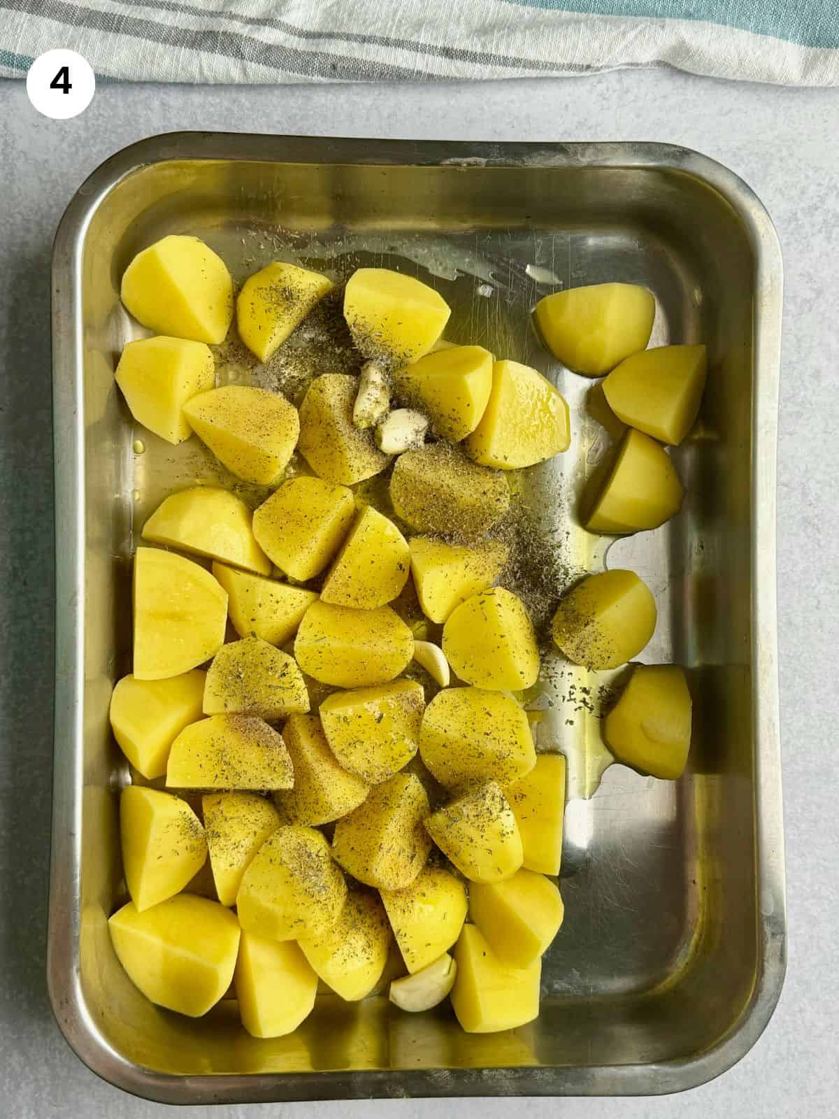 Adding the potatoes to baking tray with the rest of the ingredients.