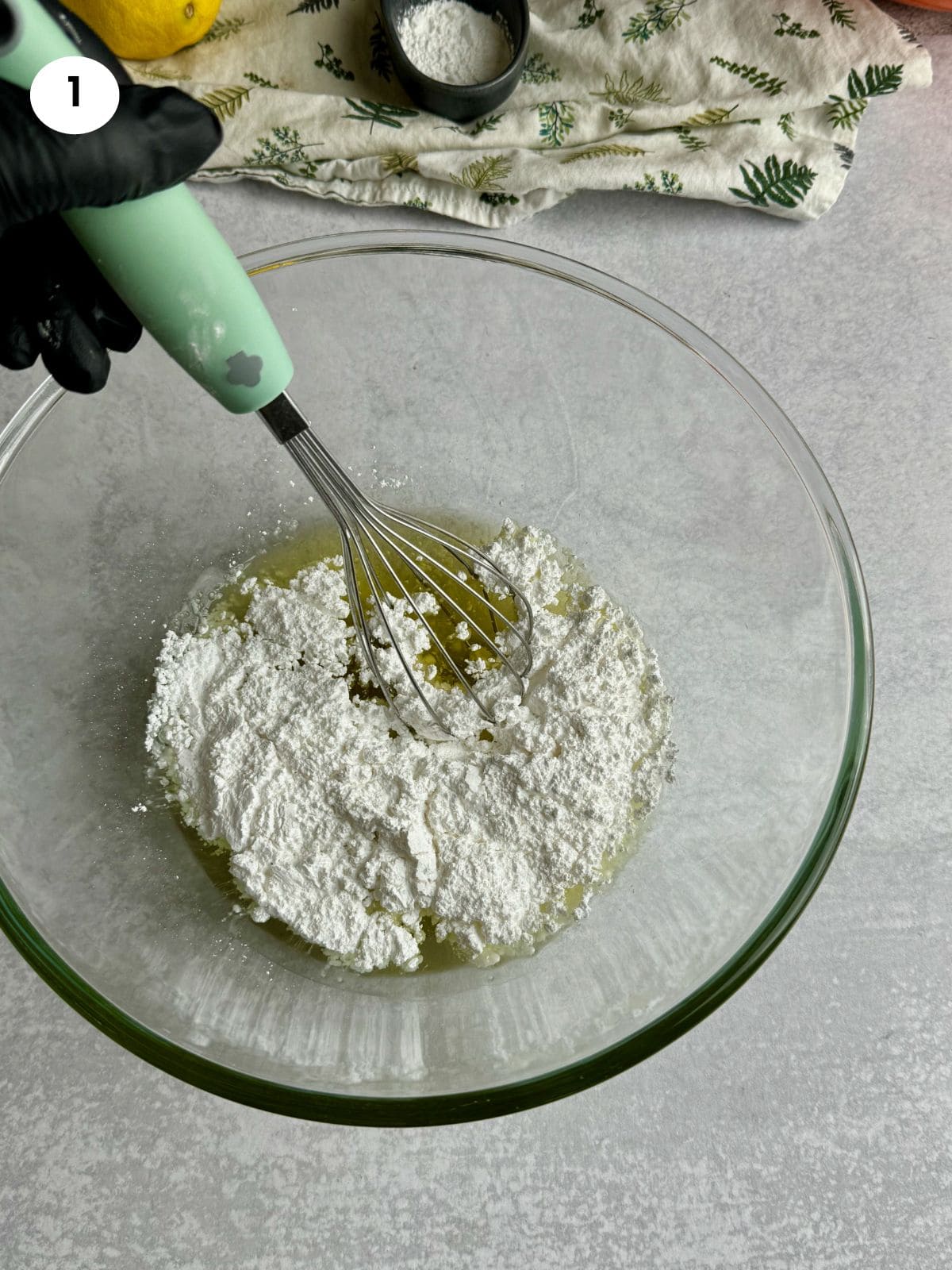 Adding oil to powdered sugar for the lemon cookies.