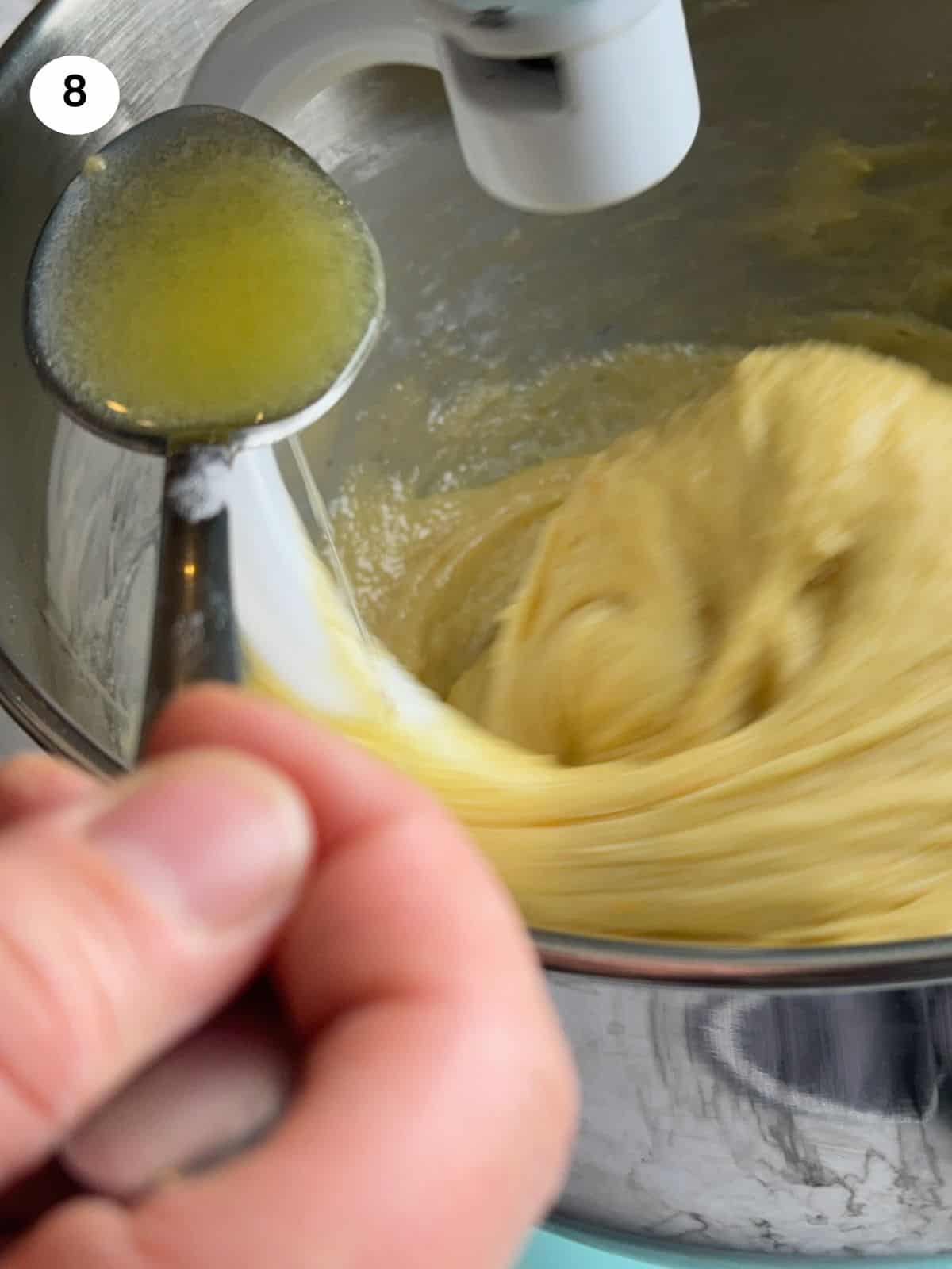 Adding the butter to the dough one spoon at a time.