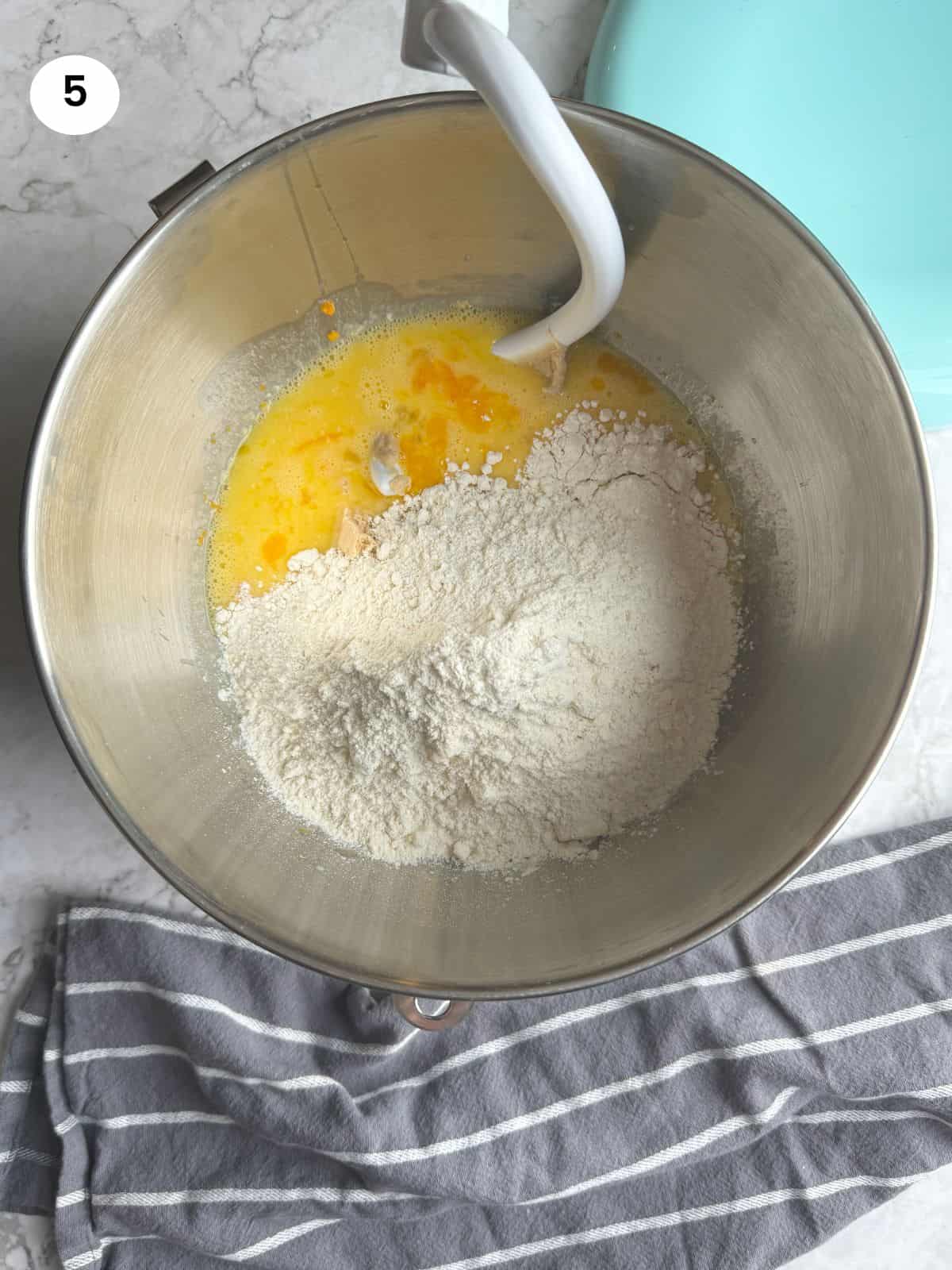 Adding the flour and yeast mixture to the bowl for mixing.