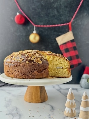 Vasilopita tsoureki on a stand with a cut piece out and the lucky coin in.