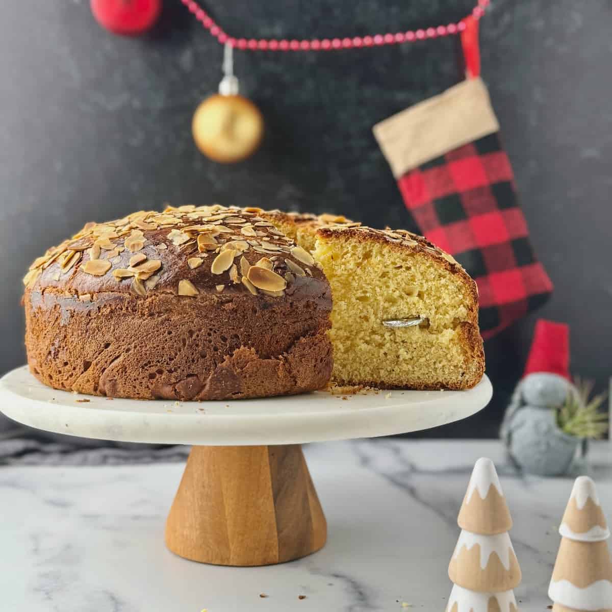 Vasilopita tsoureki on a stand with a cut piece out and the lucky coin in.