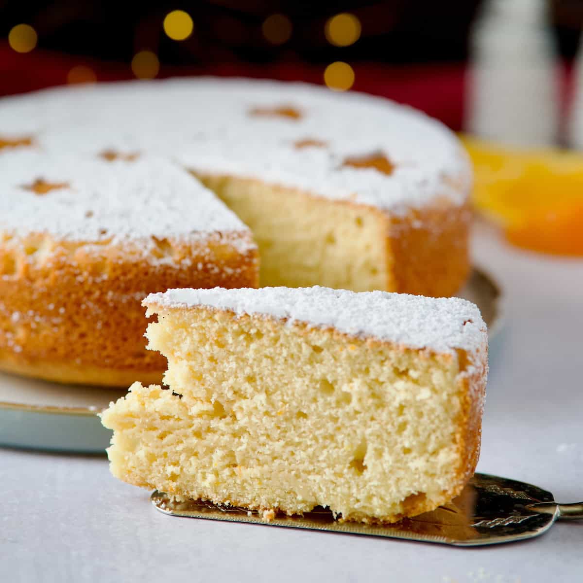 Greek new year cake decorated with powdered sugar and year date and one slice cut and served on a grey plate.