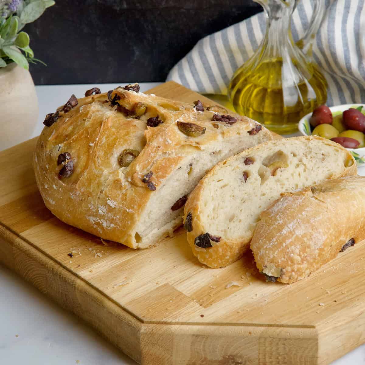 Greek olive bread loaf next to olive and olive oil.