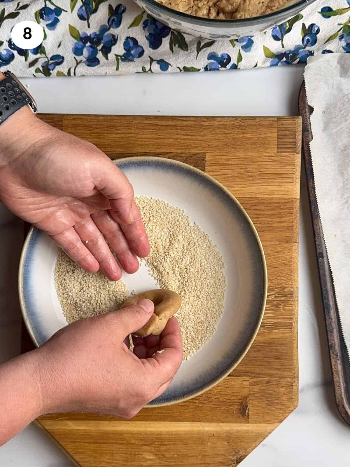 Coating the cookie with sesame seeds.