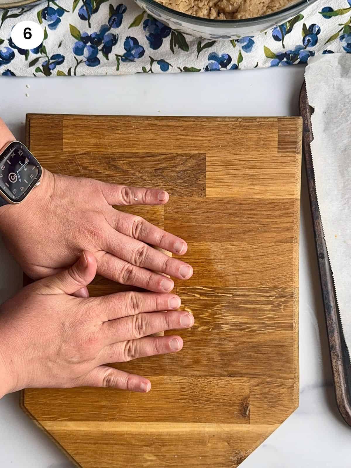 Rolling the dough into a long shape using two hands.