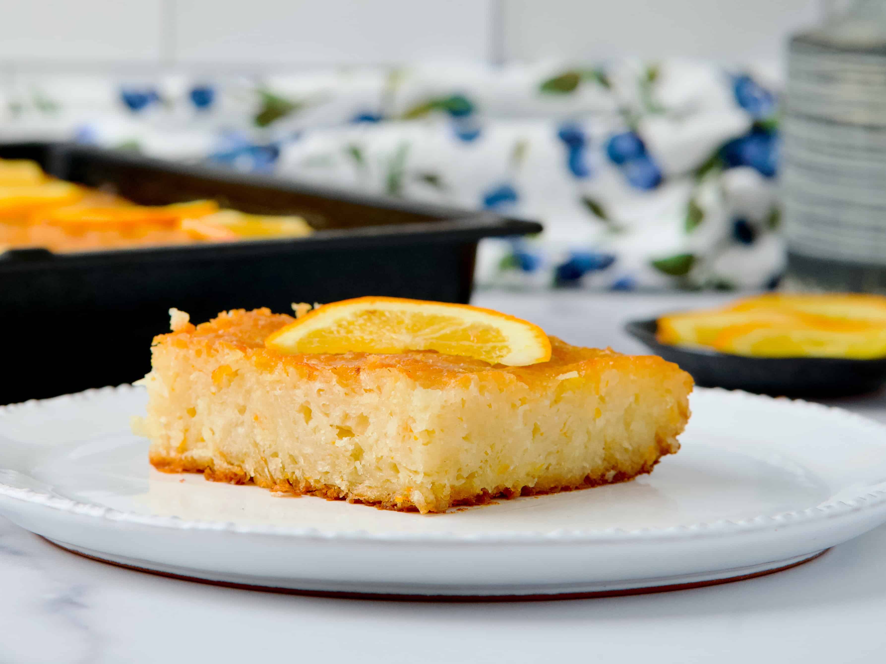 Orange cake slice served on white plate with a slice of orange on top Orange cake slice served on white plate with a slice of orange on top.