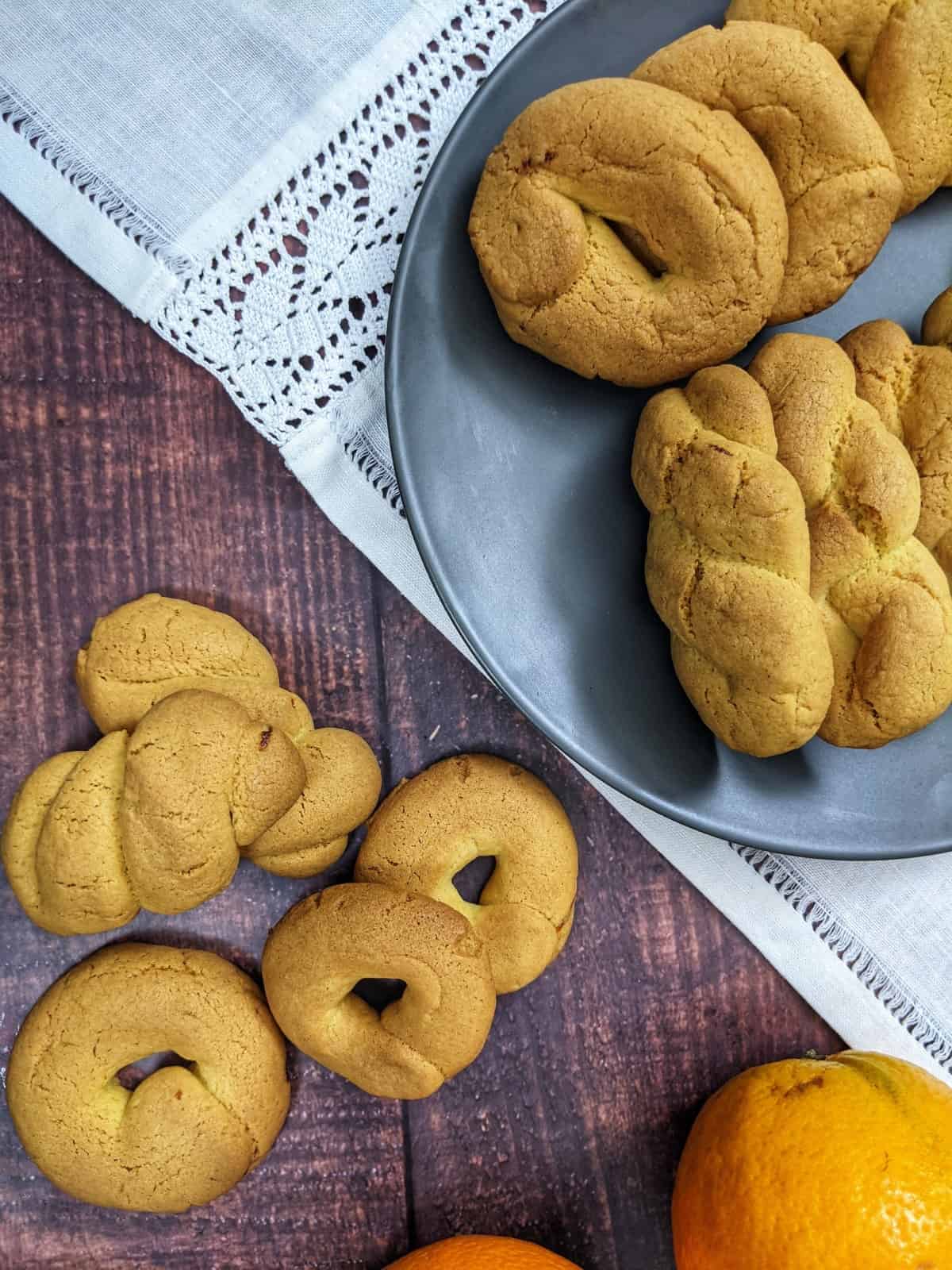 Orange cookies served on a grey plate next to oranges