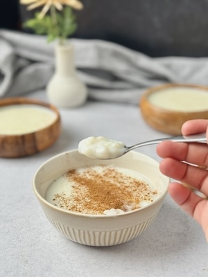 Rice pudding served in a bowl with cinnamon on top and a teaspoon full with rice pudding.