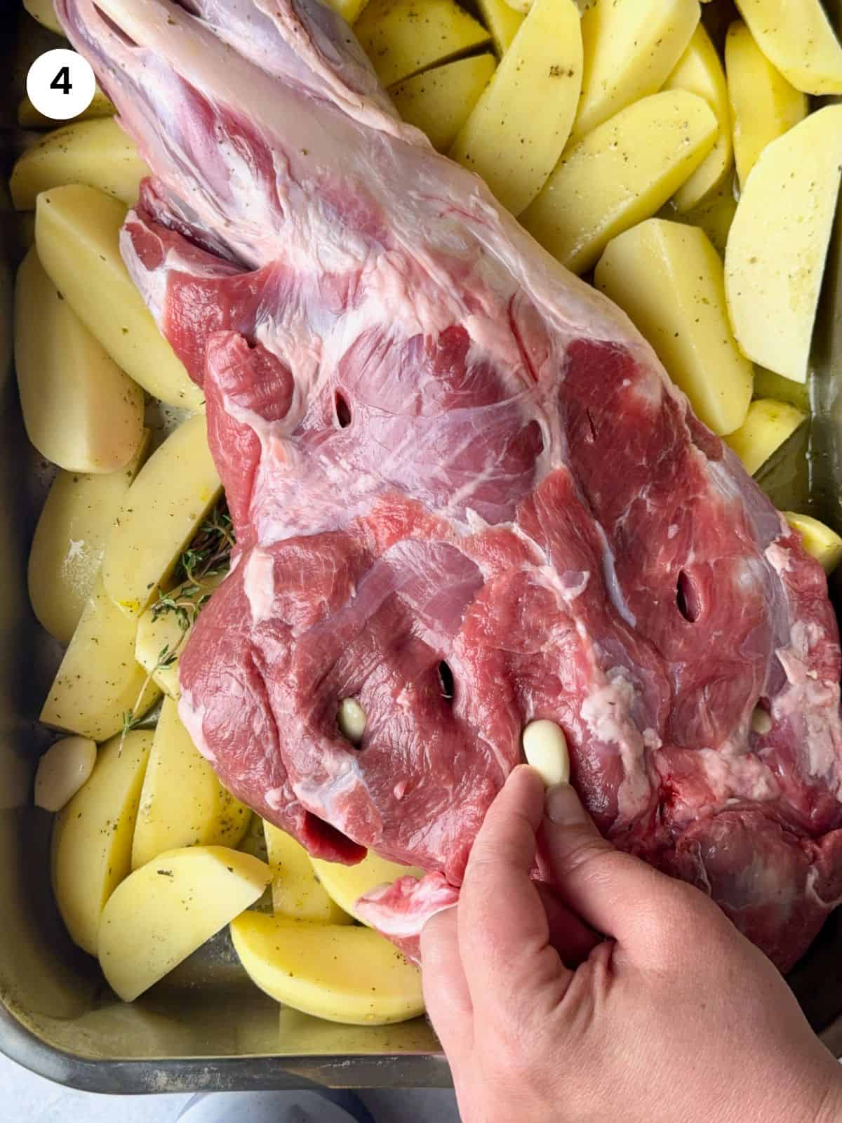 Adding garlic cloves to the lamb slits.