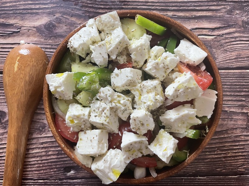 Feta cheese added to Greek salad bowl