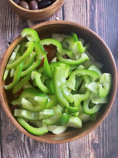 Adding sliced peppers to the salad bowl.