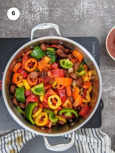 Add peppers to sausage and onions.