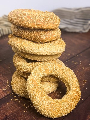 Sesame seed bagels one on top of the other and one on the side.