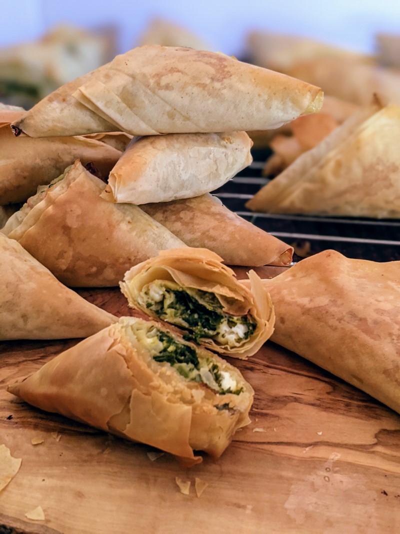 Spinach and cheese triangles stack next to each other and one in half at the front