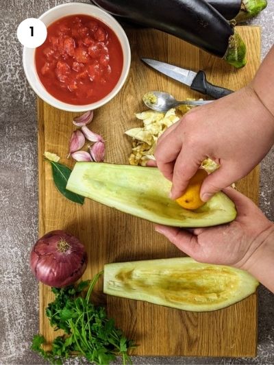 Preparing the eggplants by cutting in half and removing the flesh