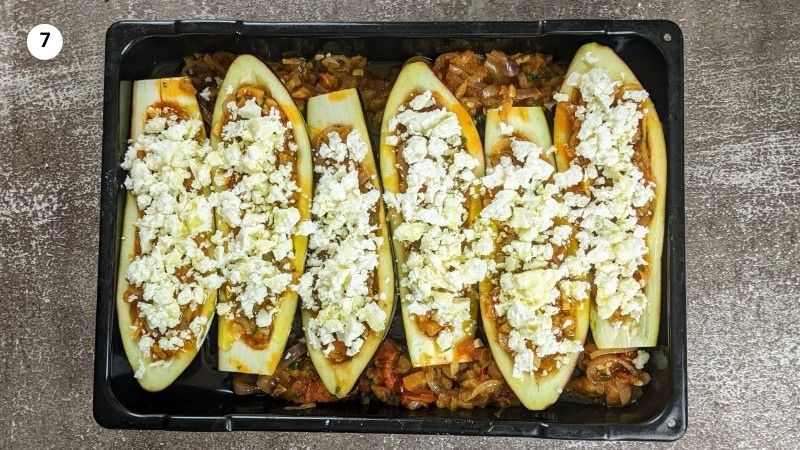 Topping up the eggplants with feta cheese before putting them in the oven to bake Topping up the eggplants with feta cheese before putting them in the oven to bake.