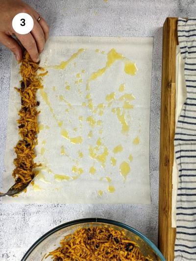 Adding the filling to the bottom of the phyllo sheet.