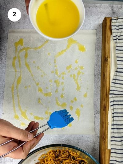 Drizzling the phyllo sheet with melted butter.