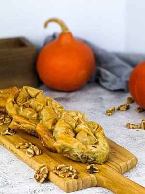 Greek sweet pumpkin pies on a wooden tray next to orange squash.