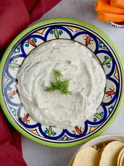 Yogurt tahini sauce served in a bowl with fresh dill on top.