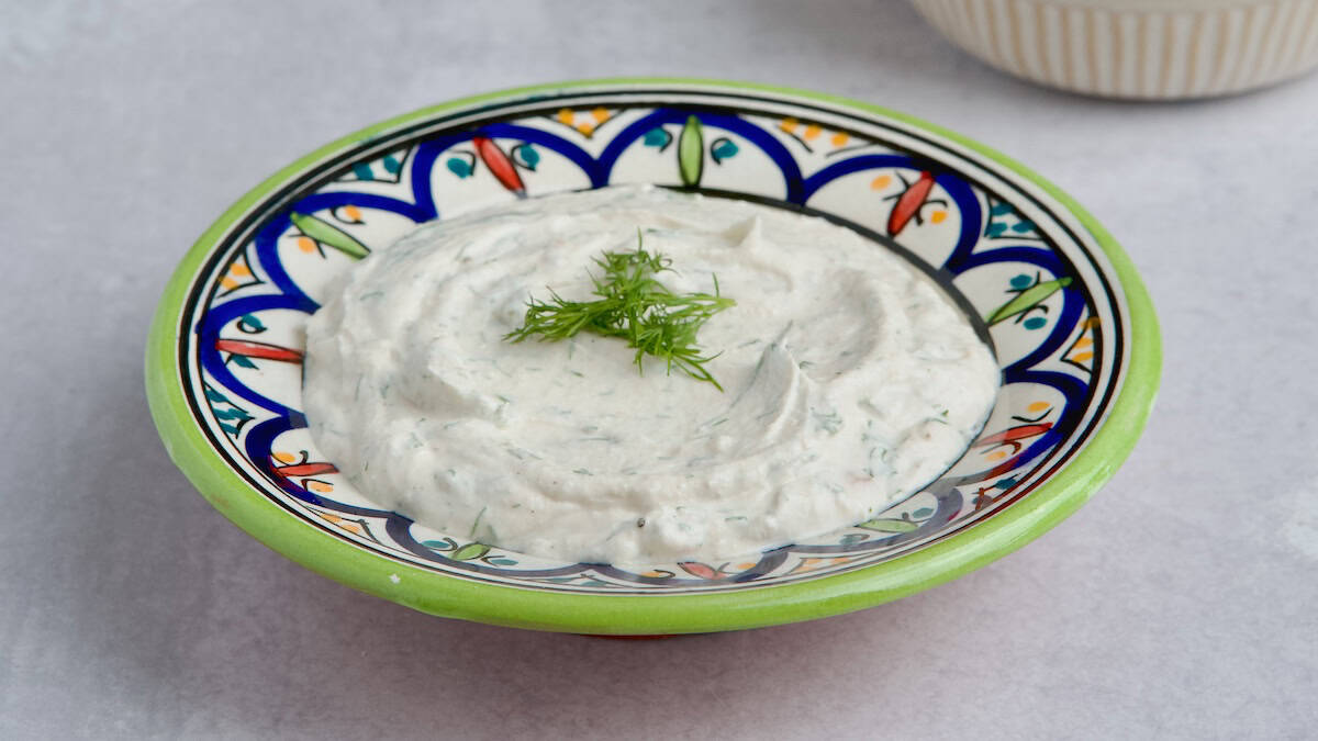 Yogurt tahini sauce served in a bowl with fresh dill on top.