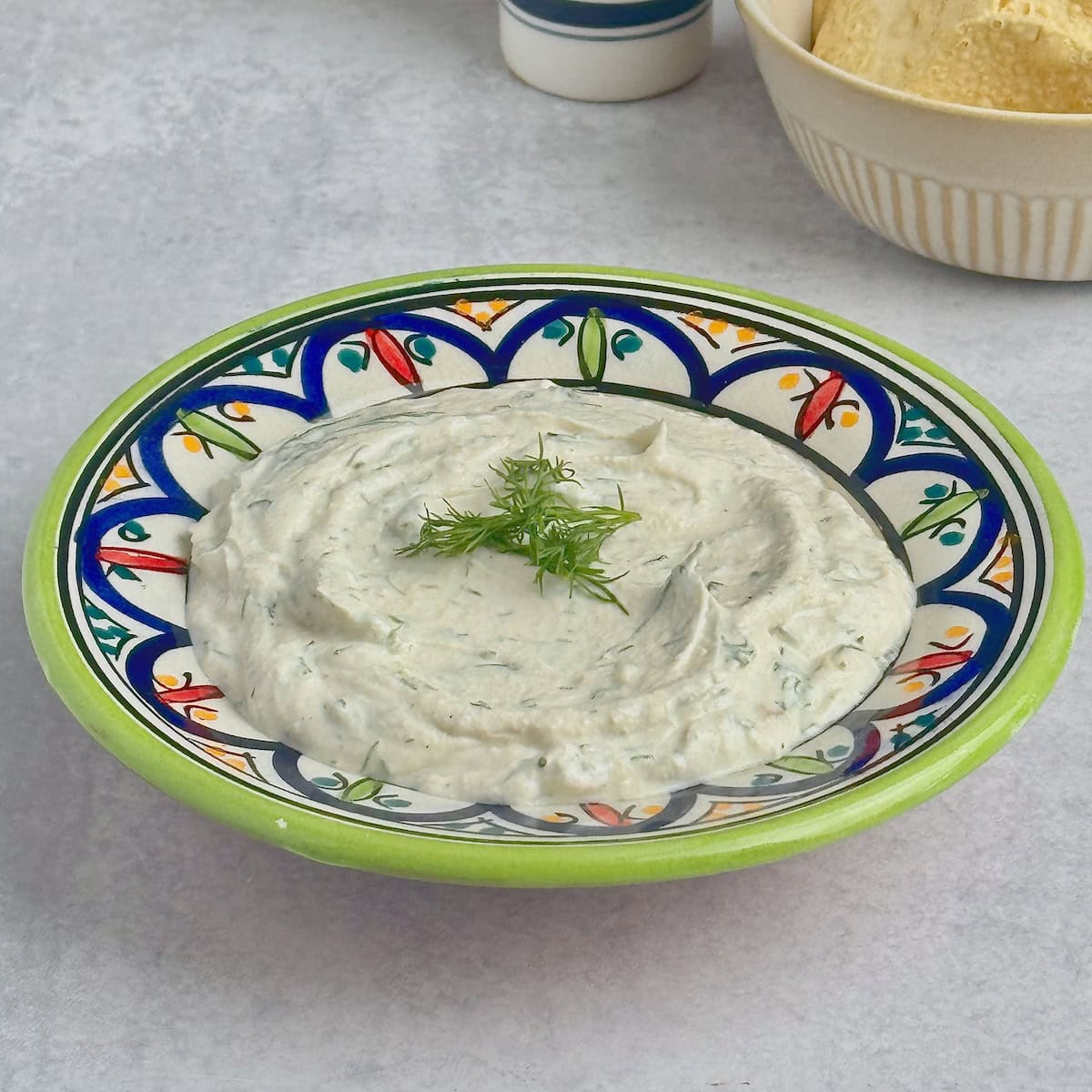 Yogurt tahini sauce served in a bowl with fresh dill on top.