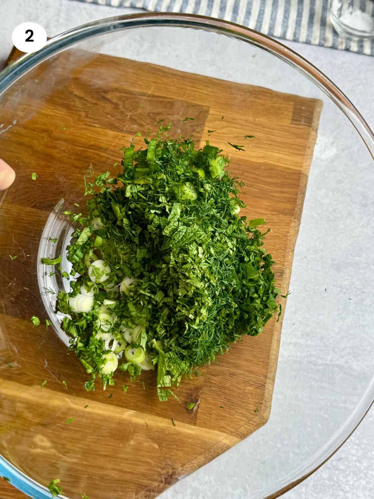 Chopped fresh herbs and onions in a bowl.