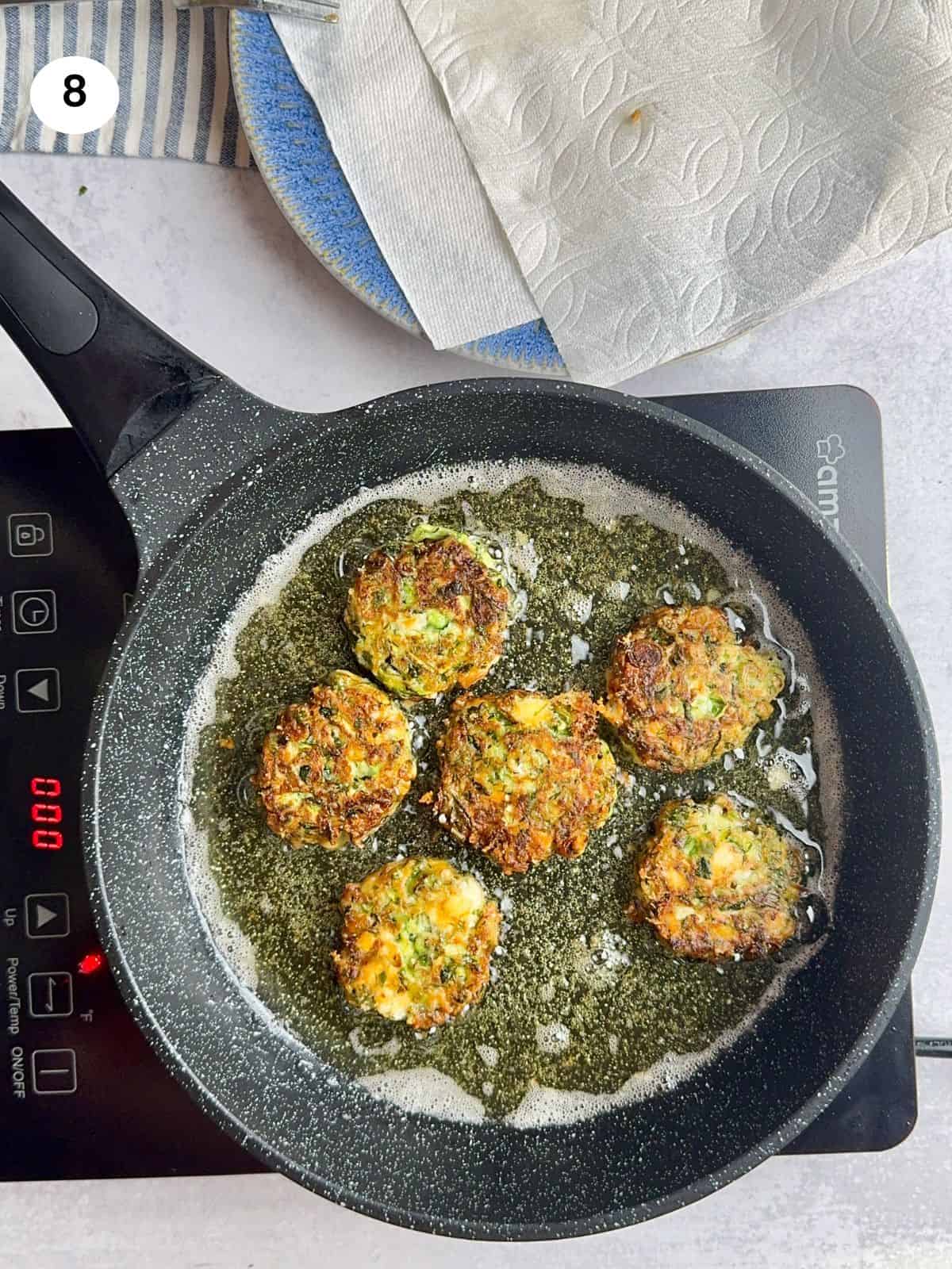 Zucchini fritters flipped to cook on the other side.