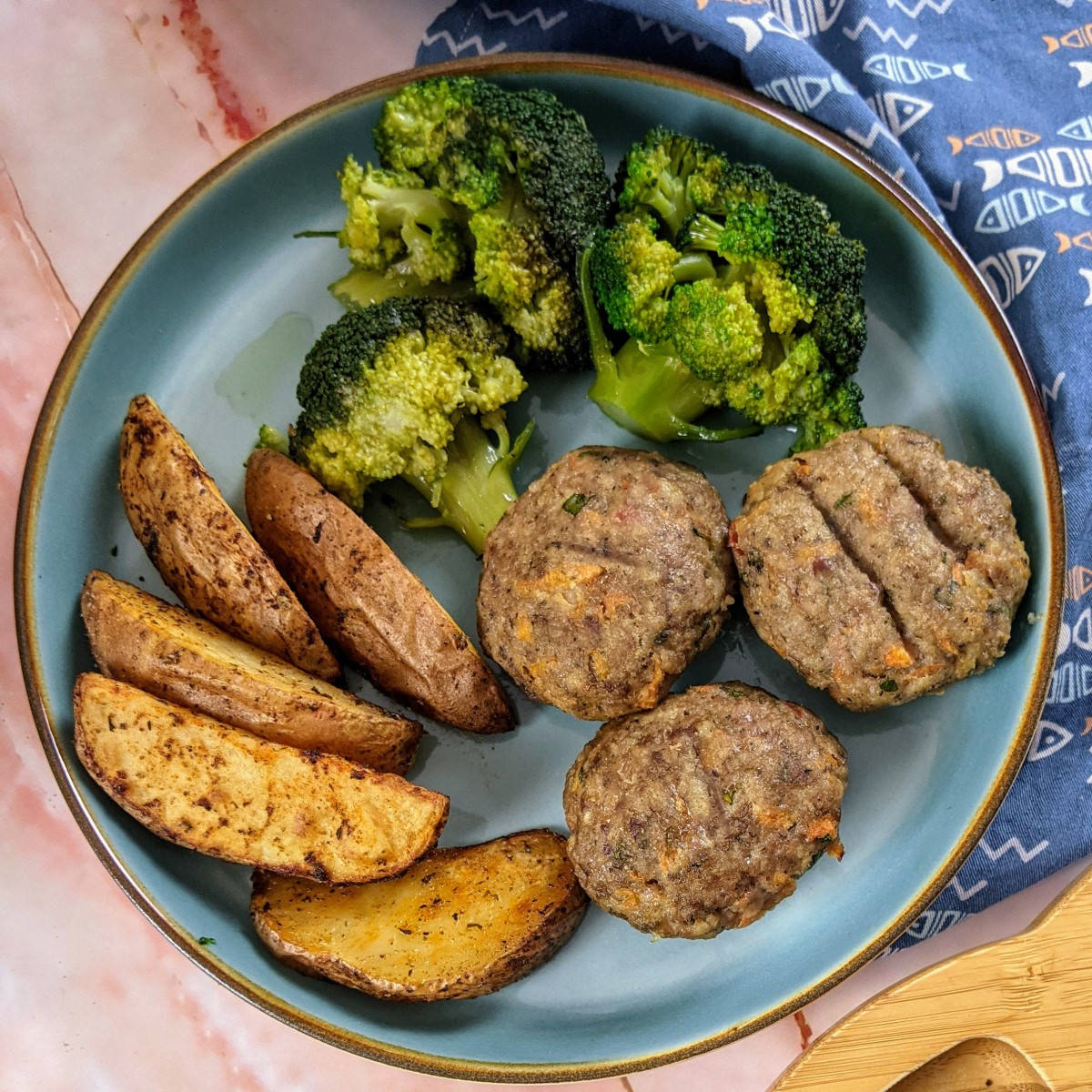 Biftekia served with wedges and broccoli for adult and toddler