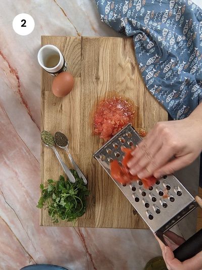 Grating the tomato for the mixture.