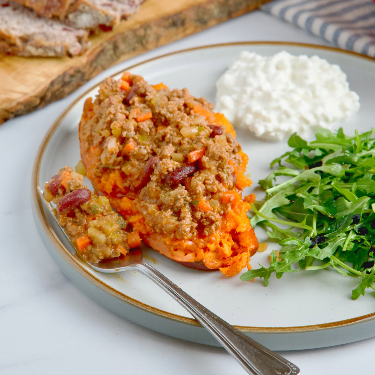 Loaded sweet potato with arugula salad and cottage cheese on the side.