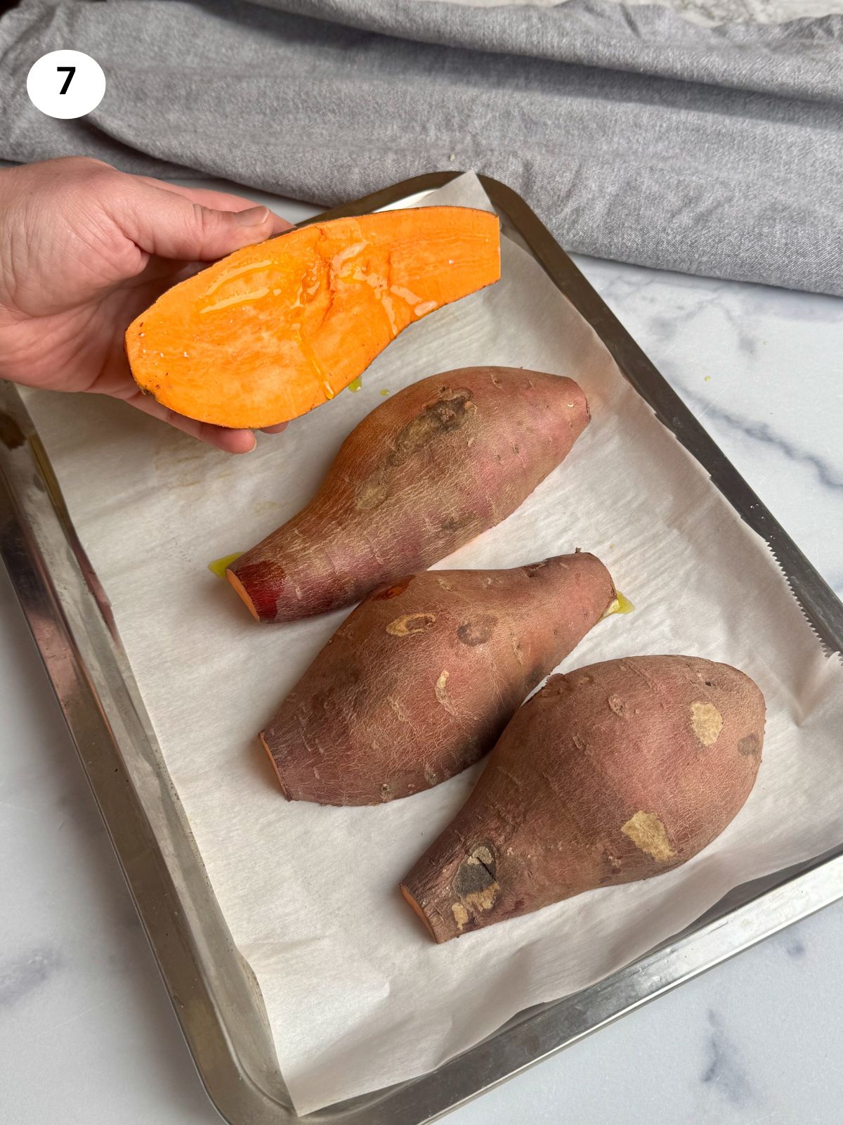 Halved sweet potatoes on a sheet pan.