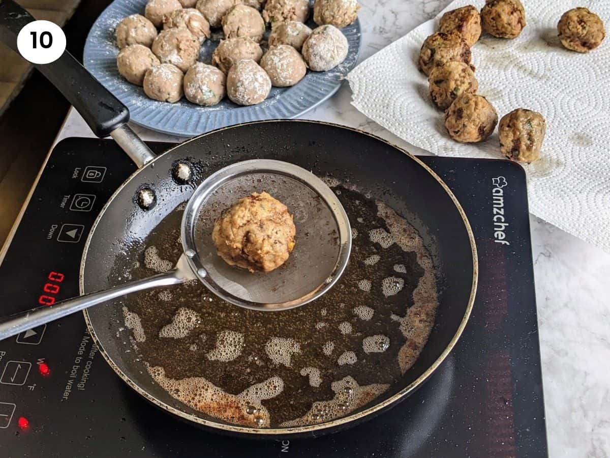 Using a slotted spoon to remove each meatball from the pan.