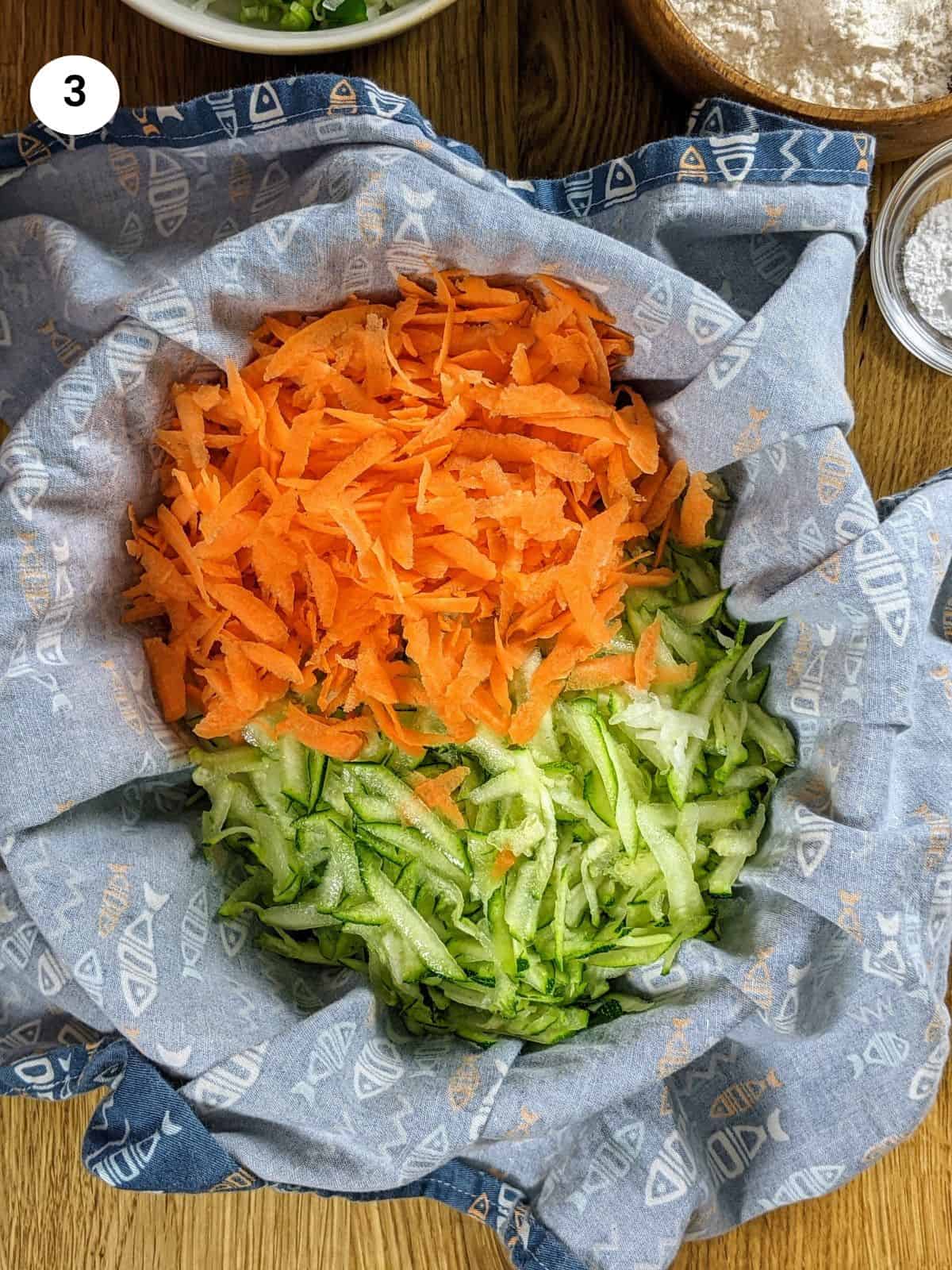 Adding grated carrot, zucchini, kohlrabi inside a tea towel.