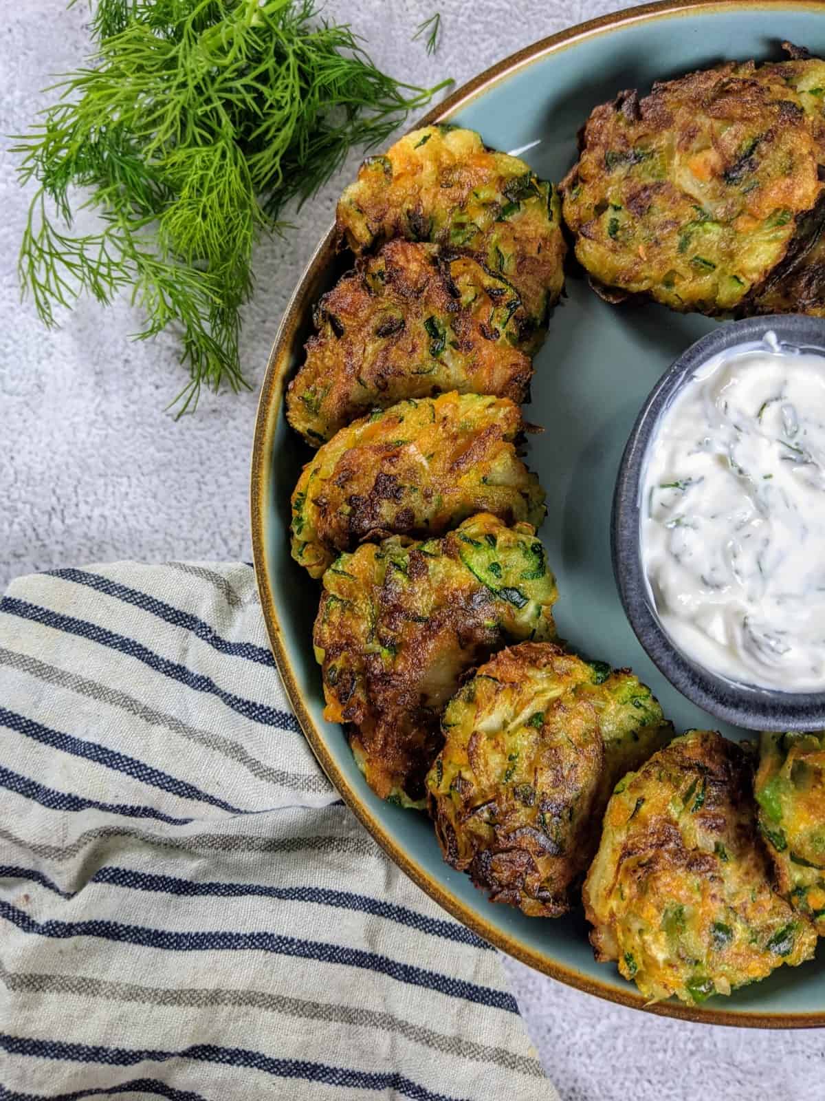 kohlrabi fritters stack on top of each other next to bowl with yoghurt dip