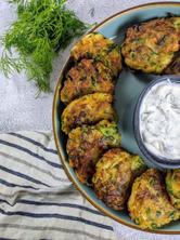 Kohlrabi fritters placed in a circle on a blue plate with yogurt dip in the middle.