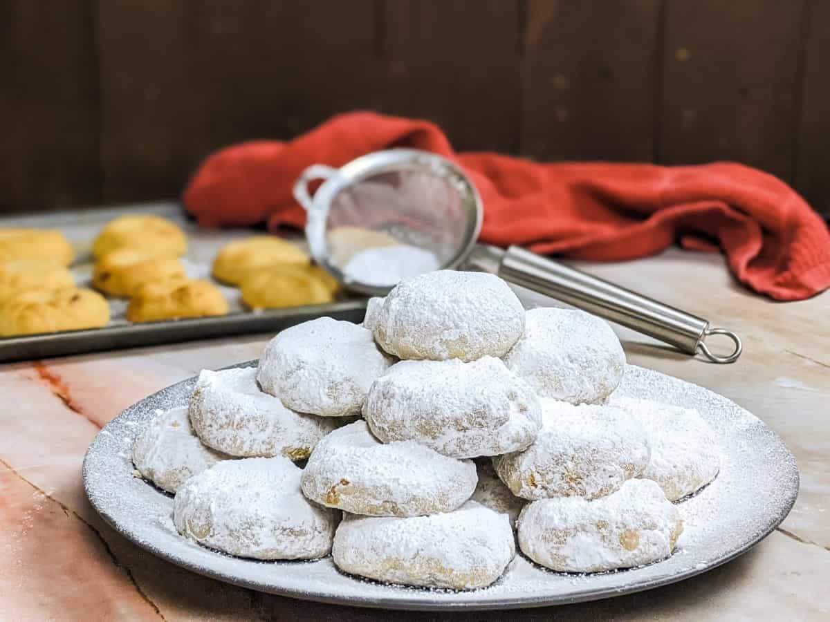 Kourabiedes served on a grey plate and dusting with powdered sugar