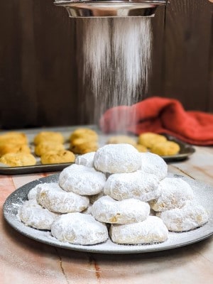 Kourabiedes served on a grey plate and dusting with powdered sugar.
